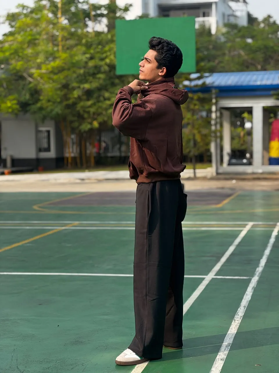 Model in the Earth brown FAZAL hoodie and wide-leg trouser on an outdoor court